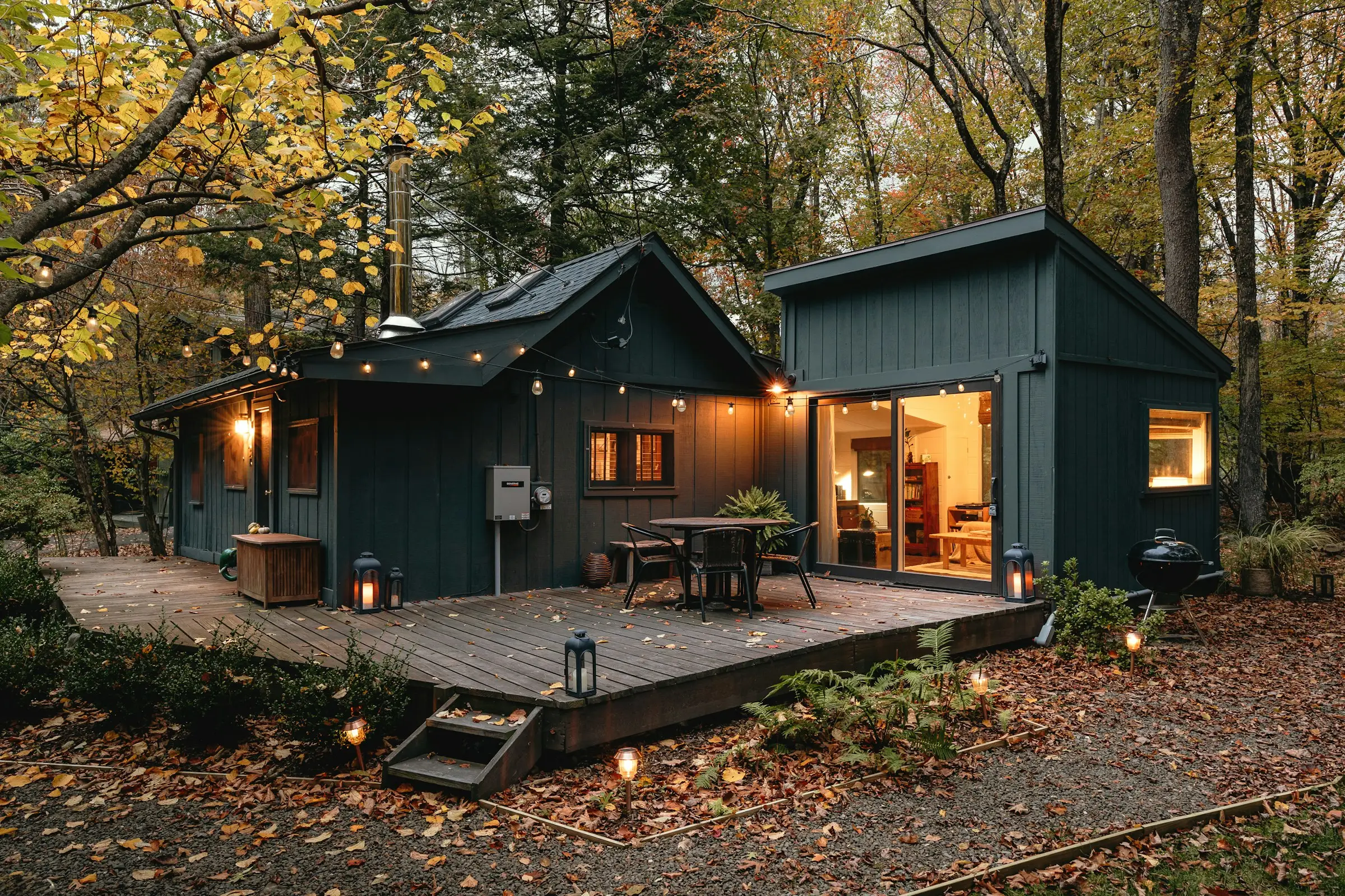 Cabañas de madera oscura con terraza y luces encendidas en el bosque
