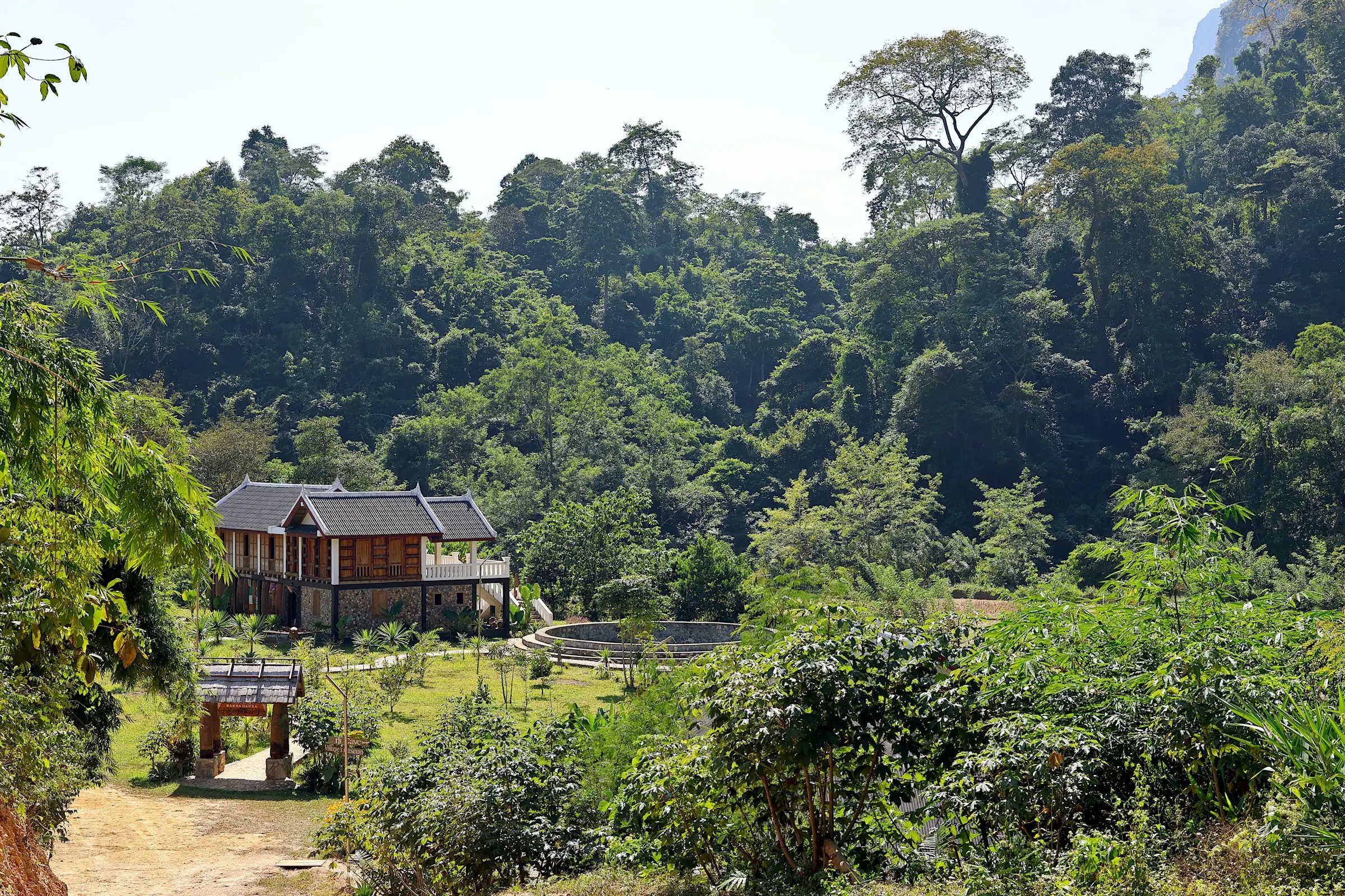 Casa de madera de techo oscuro en un valle con bosque frondoso
