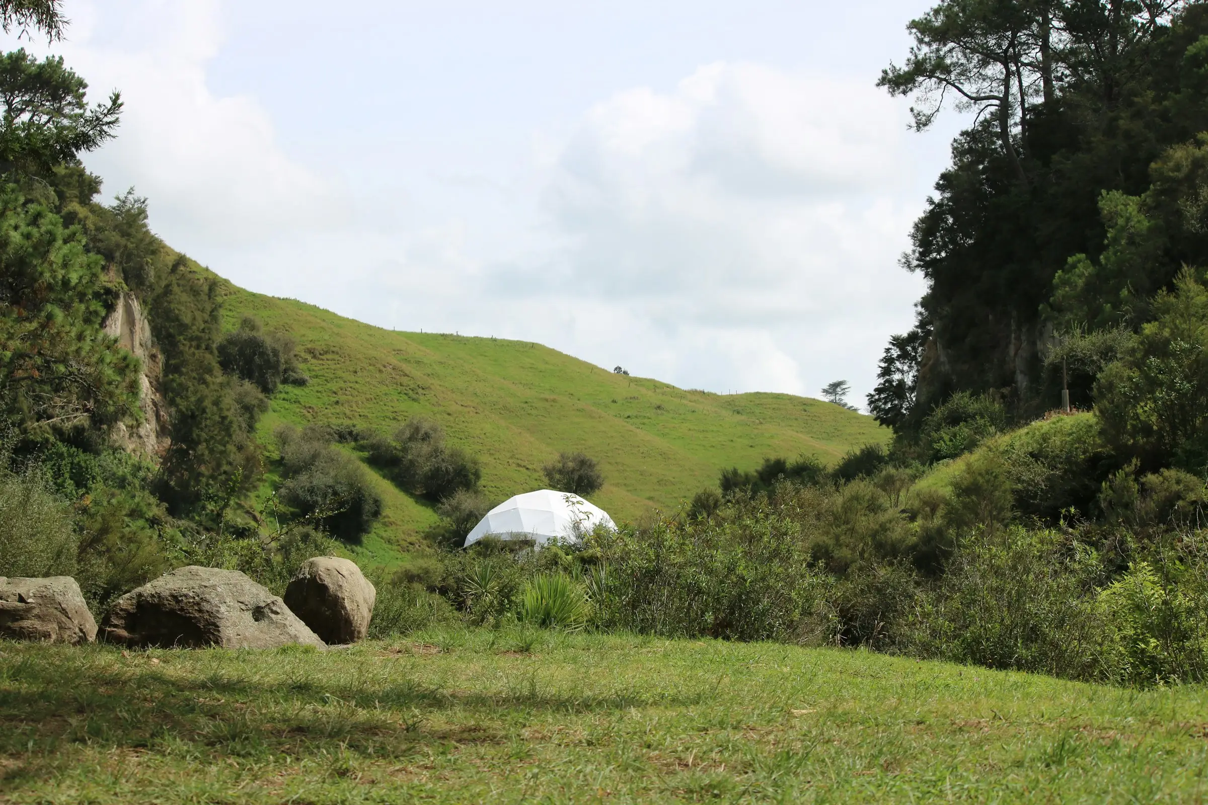 Domo blanco en un valle verde rodeado de colinas y bosque