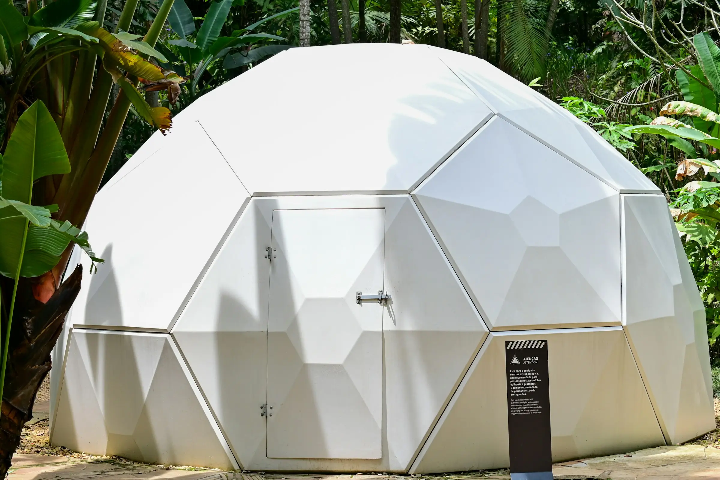 Domo geodésico blanco rodeado de vegetación tropical