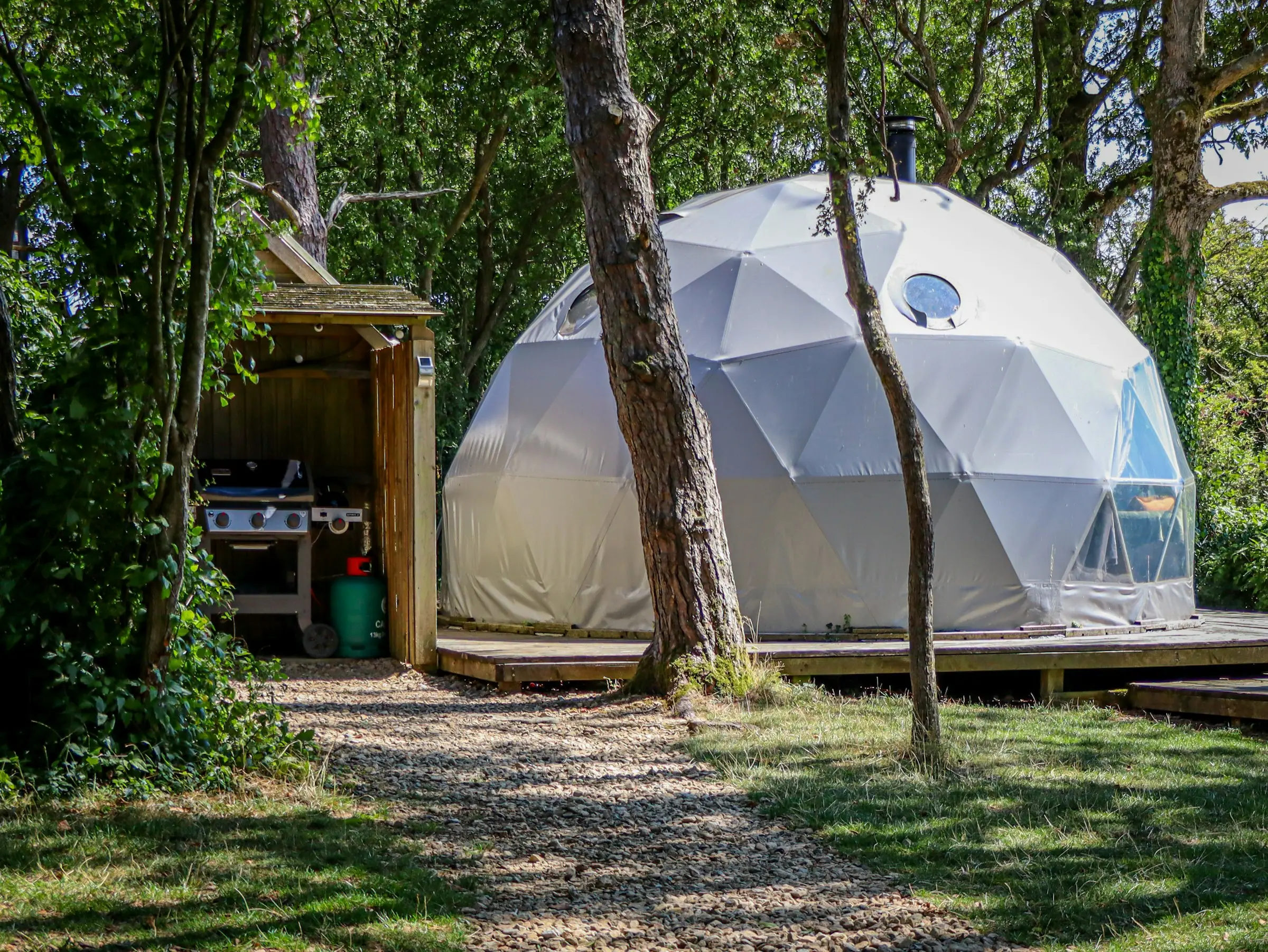Domo geodésico blanco con cocina al aire libre en medio del bosque
