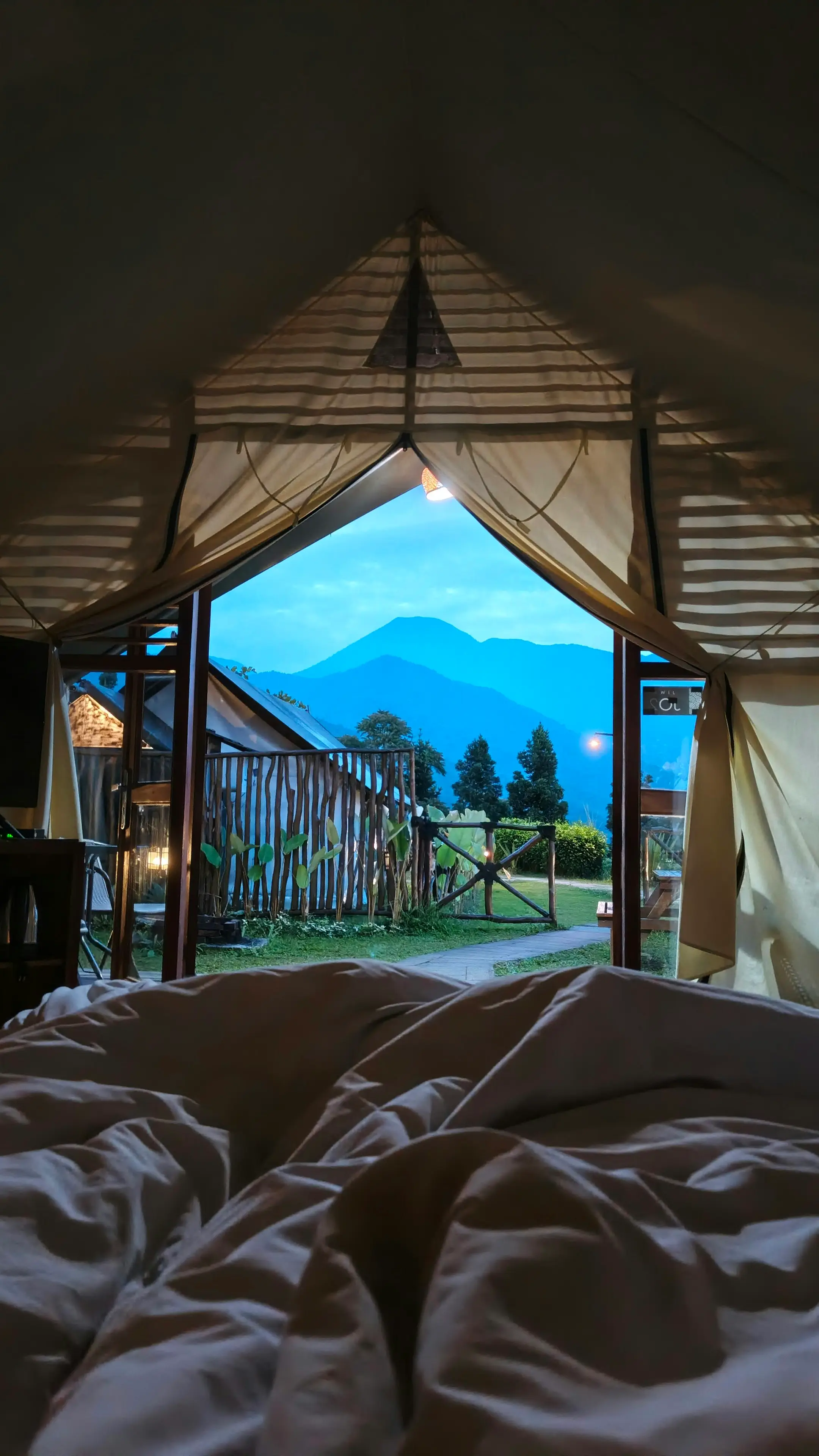 Vista de las montañas desde la cama, a través de la entrada abierta de una carpa
