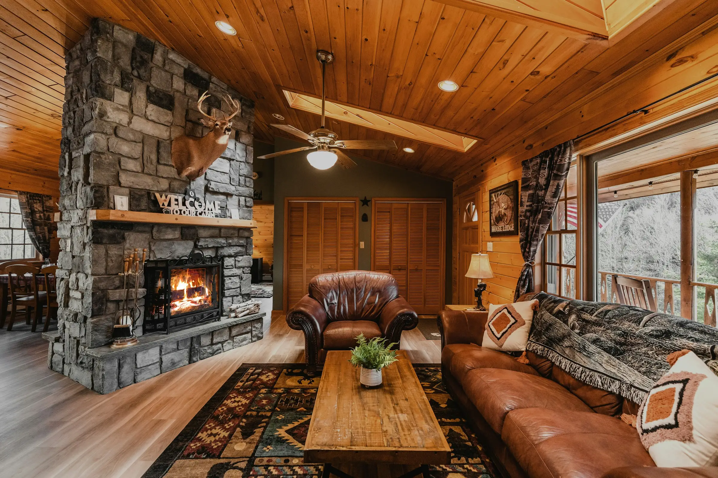 Sala de cabaña con chimenea de piedra, sofás y techo de madera