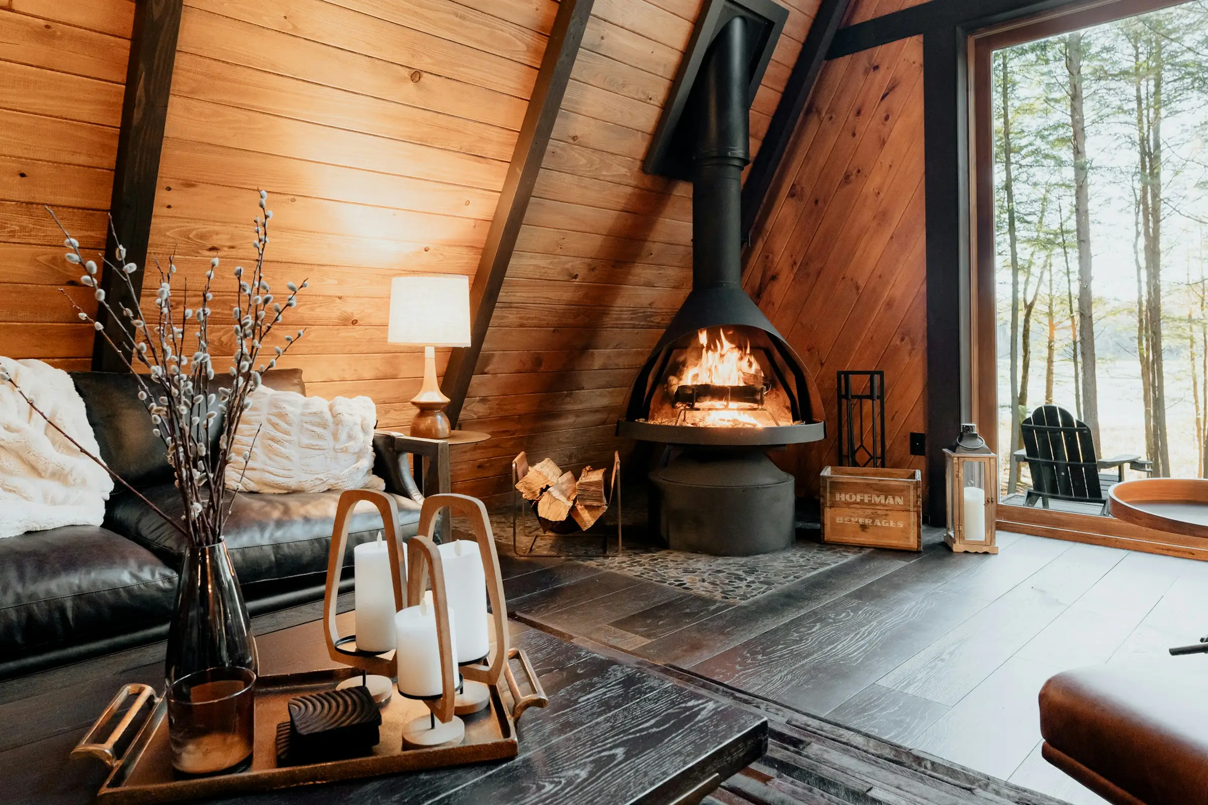 Sala de una cabaña A-frame con chimenea colgante y sofá