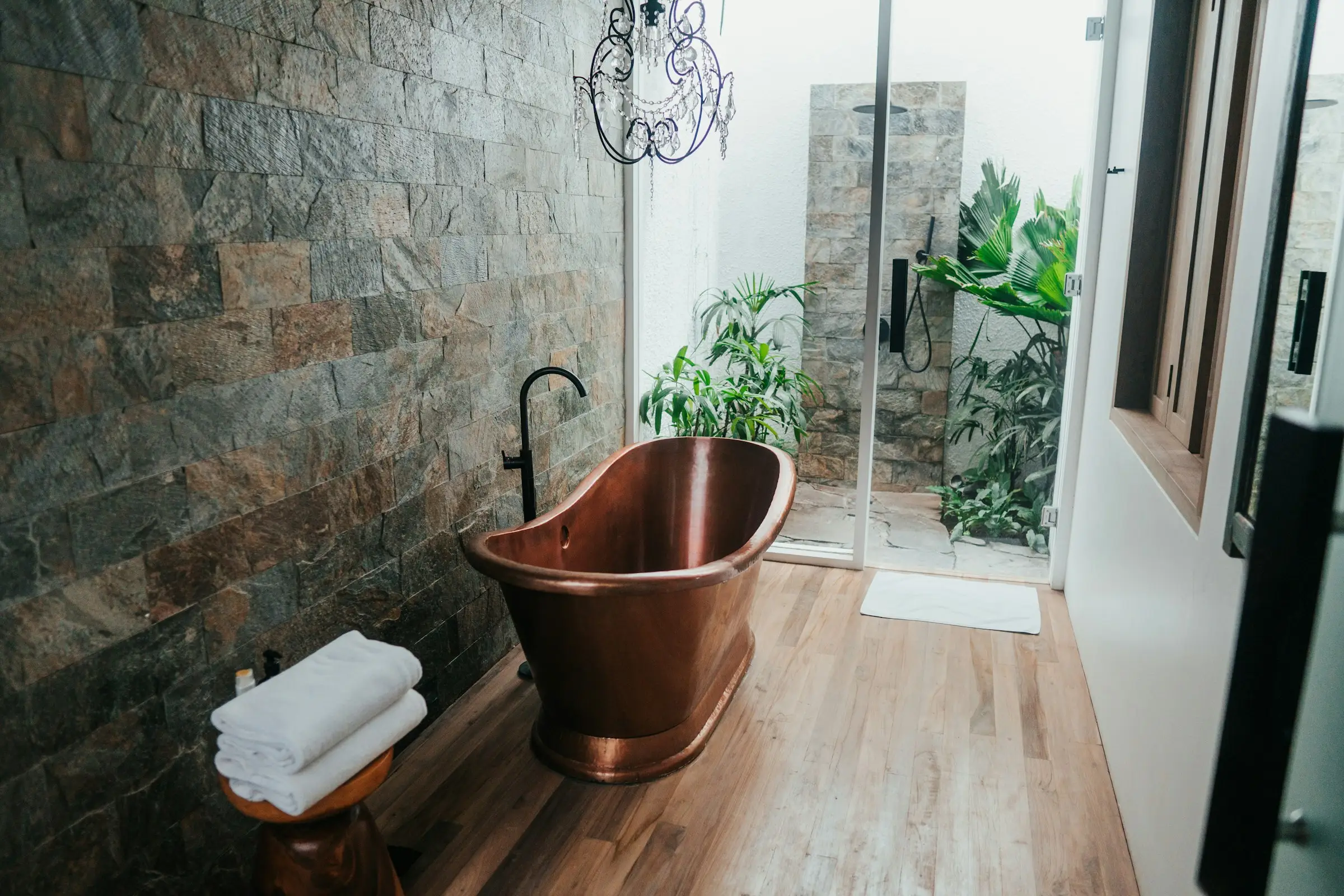 Baño con tina de cobre y pared de piedra