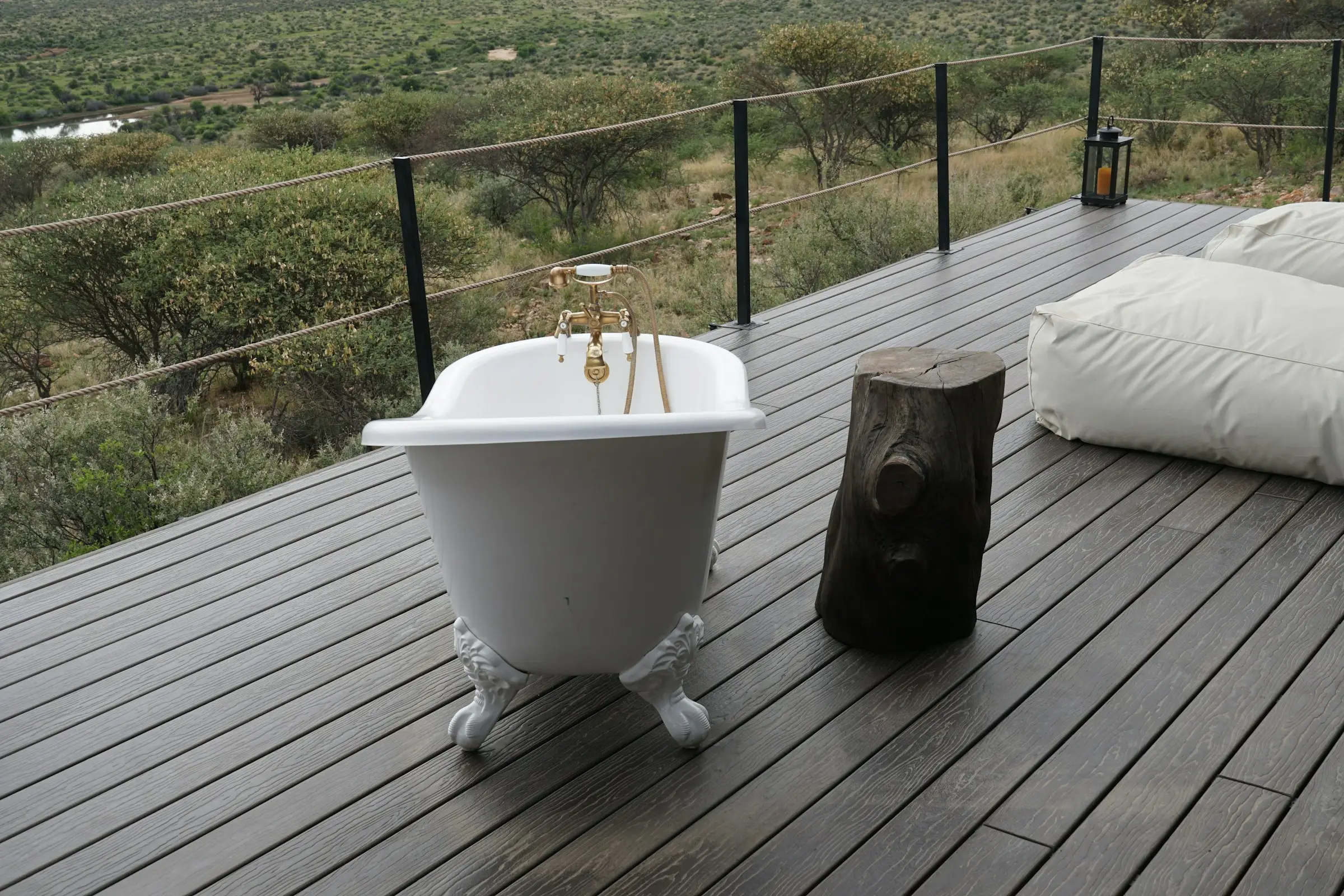 Bañera de patas sobre una terraza de madera con vista a un paisaje verde