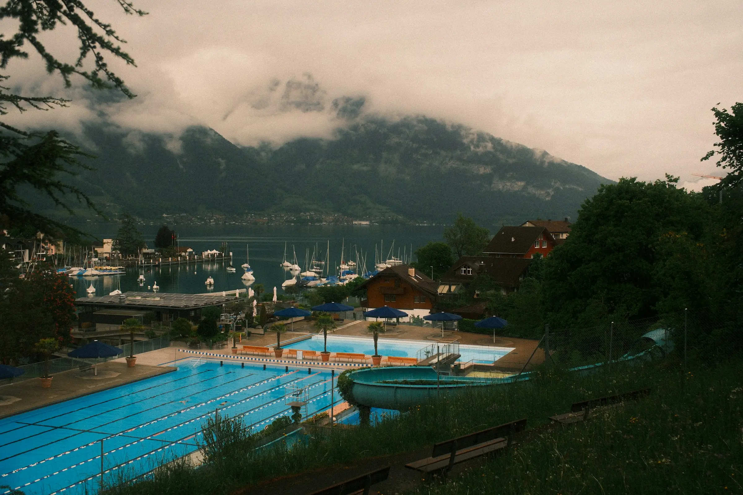 Piscina con vista a un lago y a montañas cubiertas de nubes