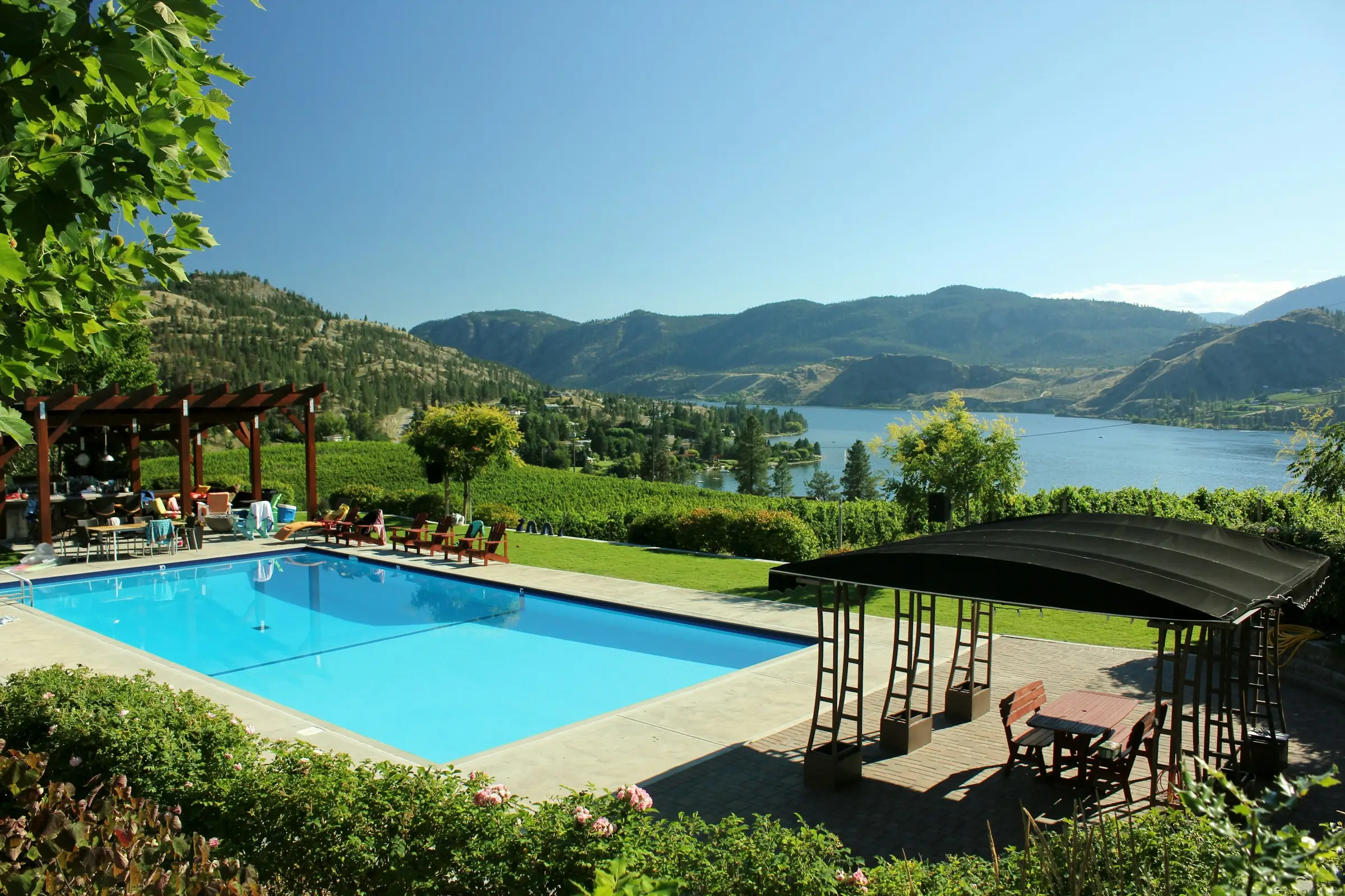 Piscina en un jardín con vista a un lago entre montañas