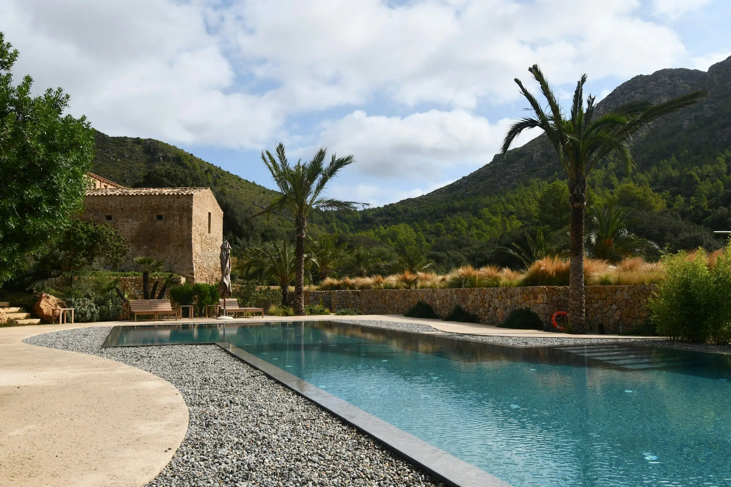 Piscina junto a una casa, con palmas y montañas alrededor