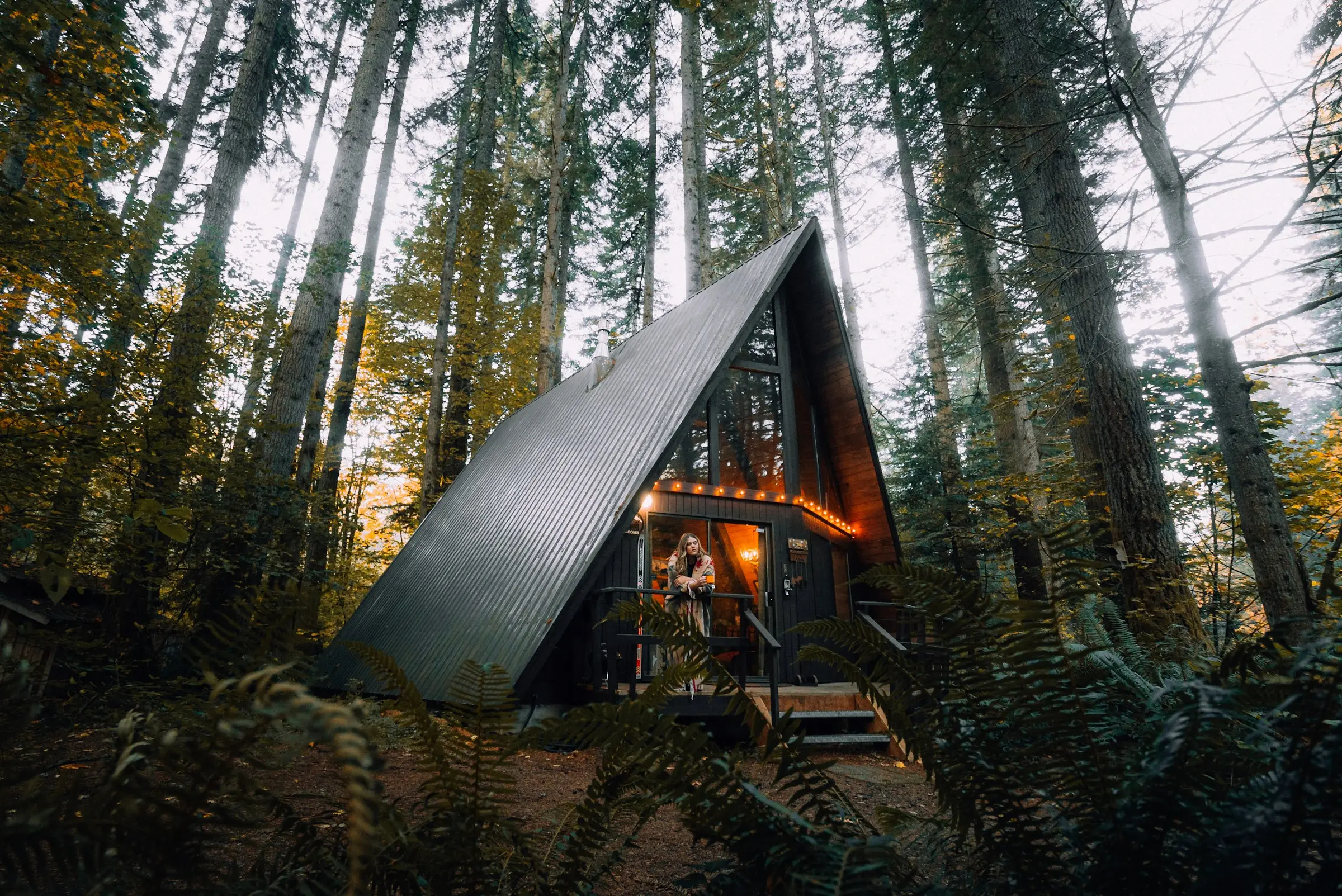 Cabaña A-frame entre los árboles altos de un bosque
