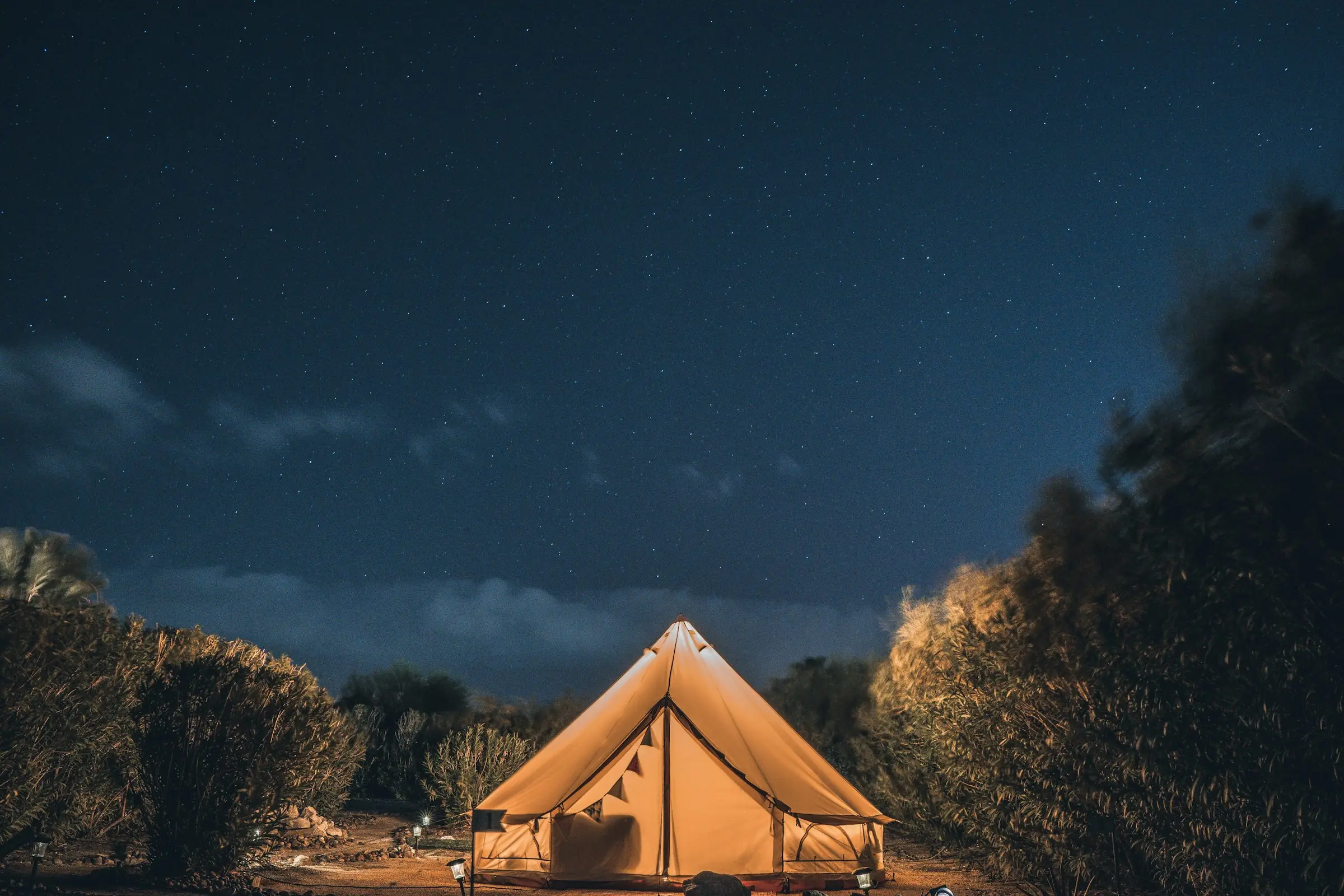 Carpa tipo campana iluminada bajo un cielo lleno de estrellas