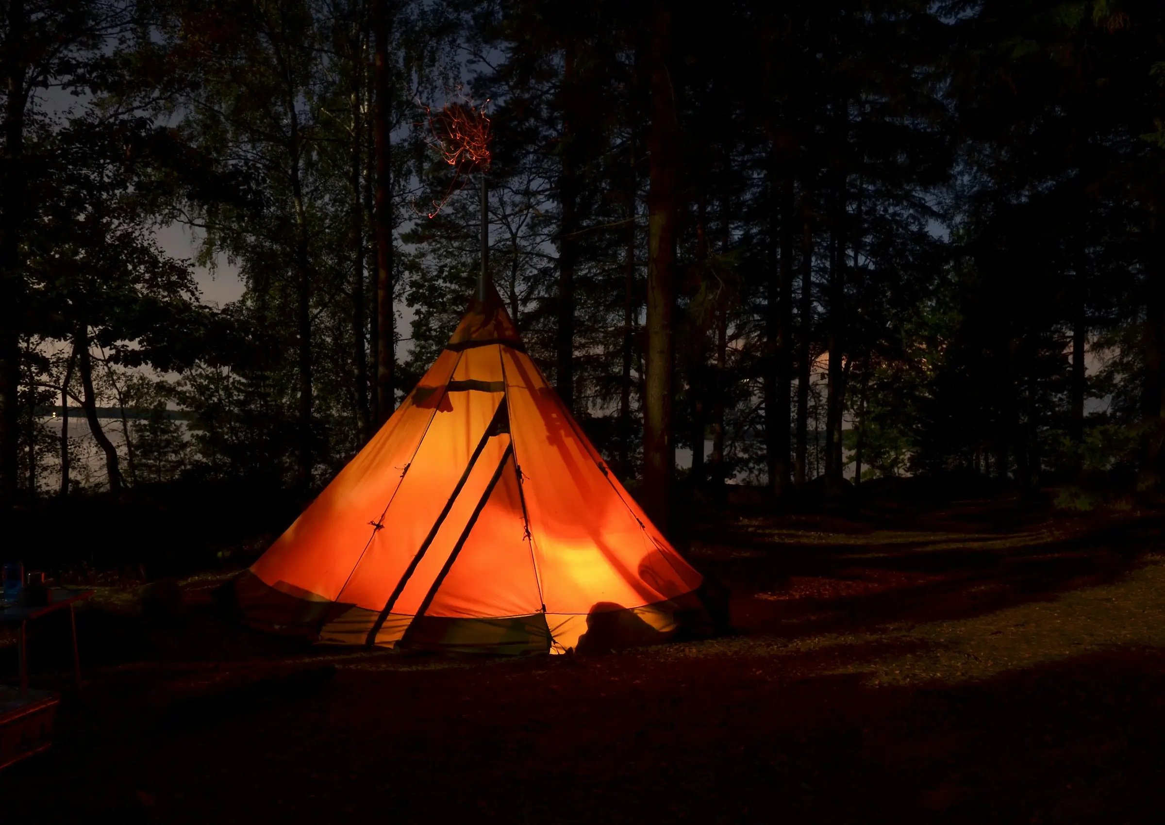 Tipi iluminado desde adentro en la noche, en medio del bosque